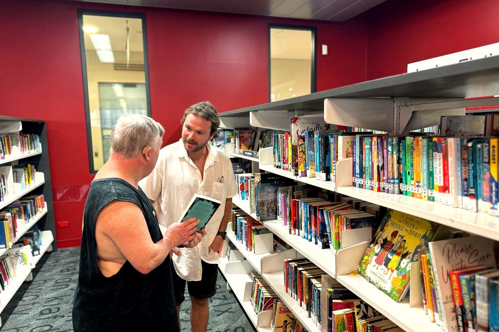 Two people looking at a book in a library