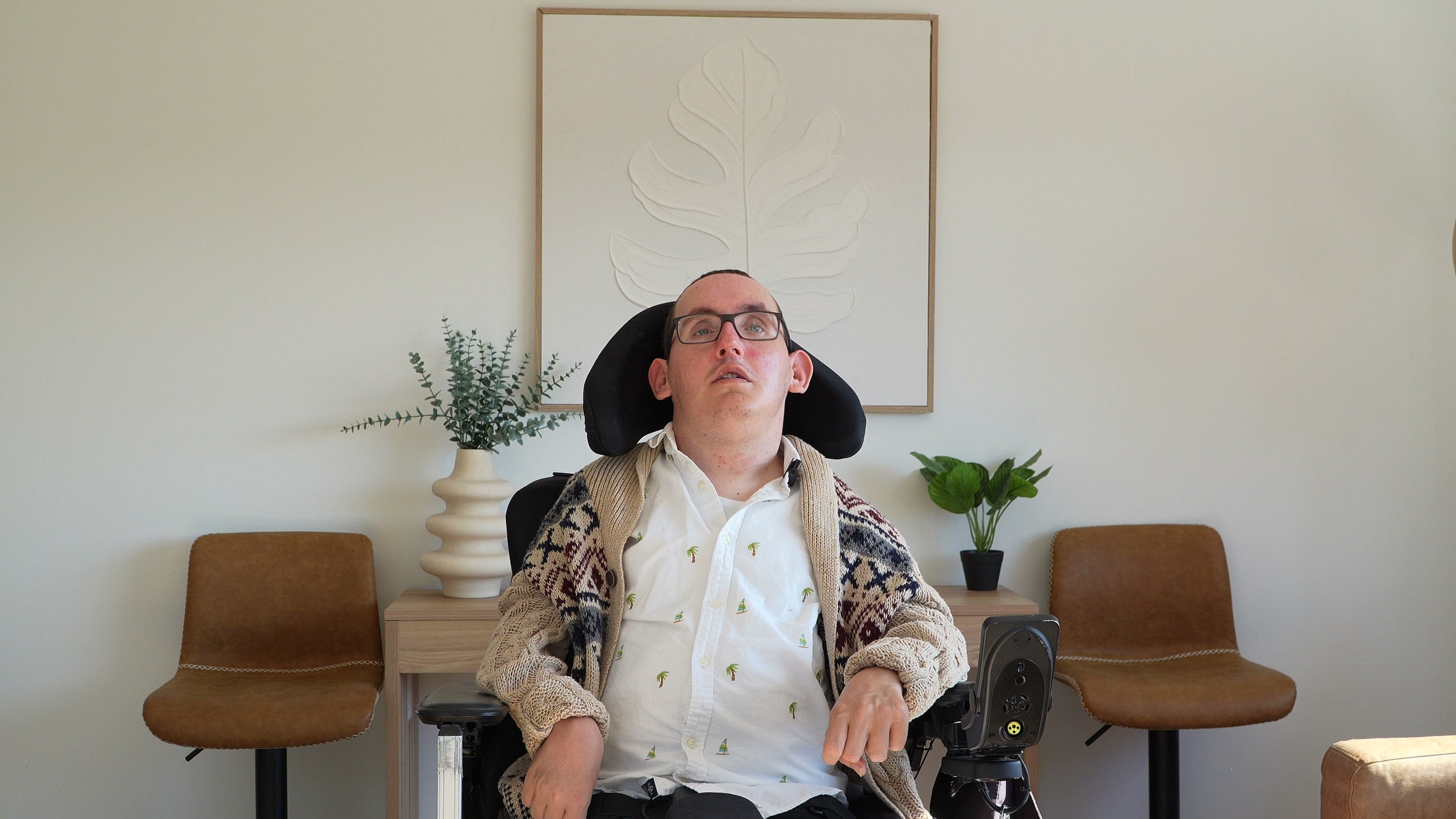A wheelchair user seated between two chairs in a living room