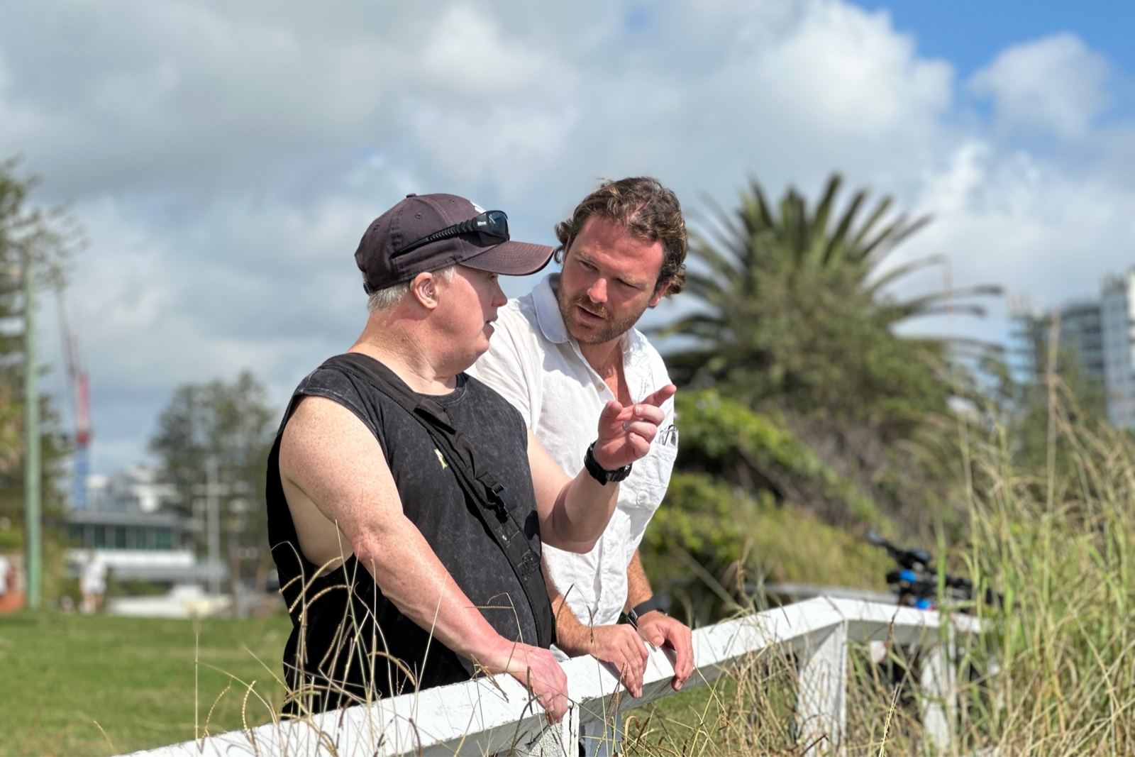 Two people talking beside a white fence outdoors
